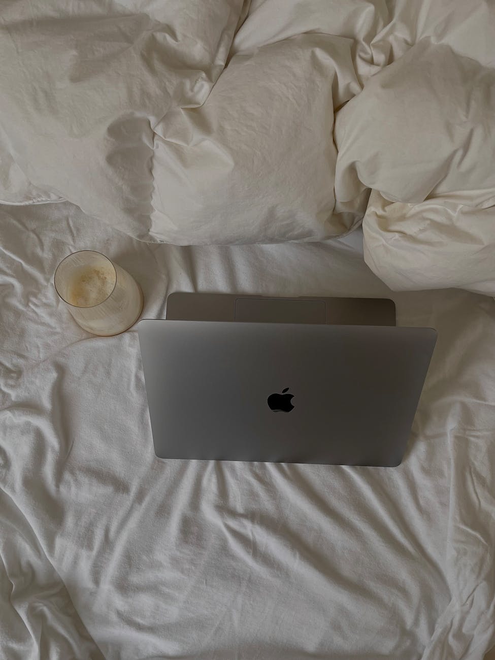 laptop and coffee in glass on bed