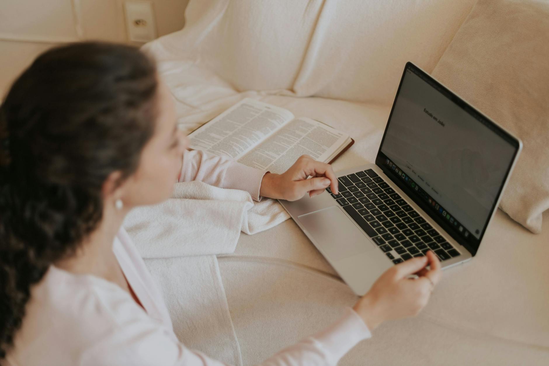 woman reading and using laptop on couch